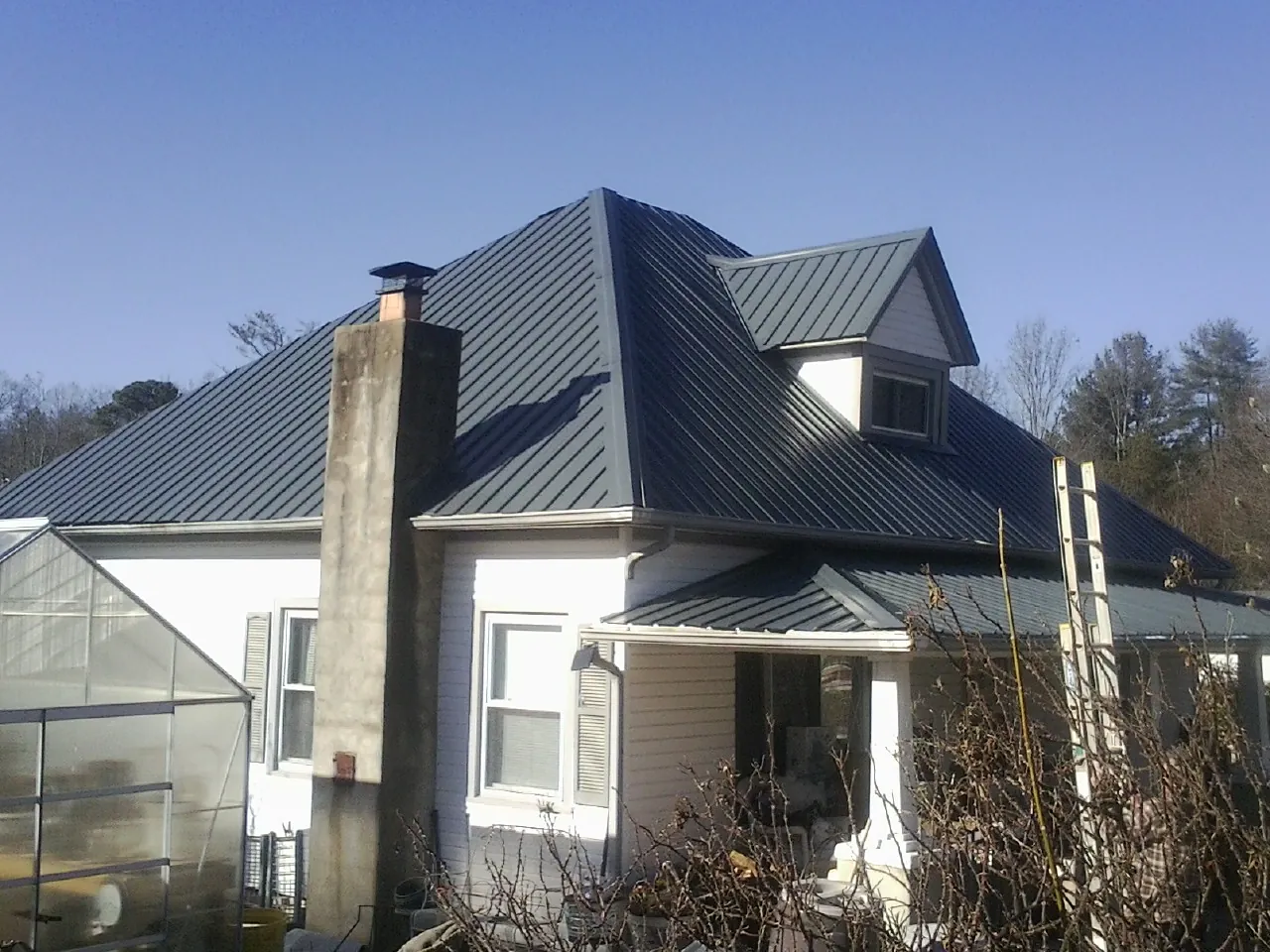 Dark blue standing seam metal roof on a white farmhouse with dormer — Slate & Tile Roof Repair by Roofing Brothers in Beale Afb
