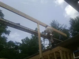Carpenter setting a ridge beam over a new addition frame — Ice Dam Removal by Roofing Brothers in Beale Afb