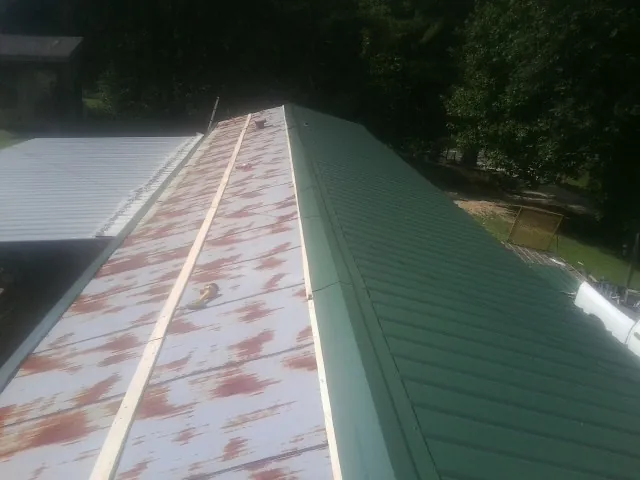 Old rusted panels beside newly installed green metal roofing — Wind Damage Roof Repair by Roofing Brothers in Beale Afb