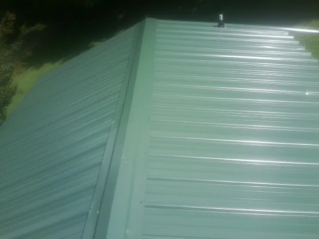 New green metal panels meeting at the ridge of a roof — Flat Roof Repair work by our crew in Beale Afb