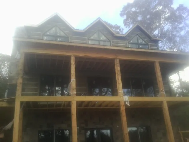 Dormers and porch framing on a large log home under construction — Roof Coating work by our crew in Beale Afb