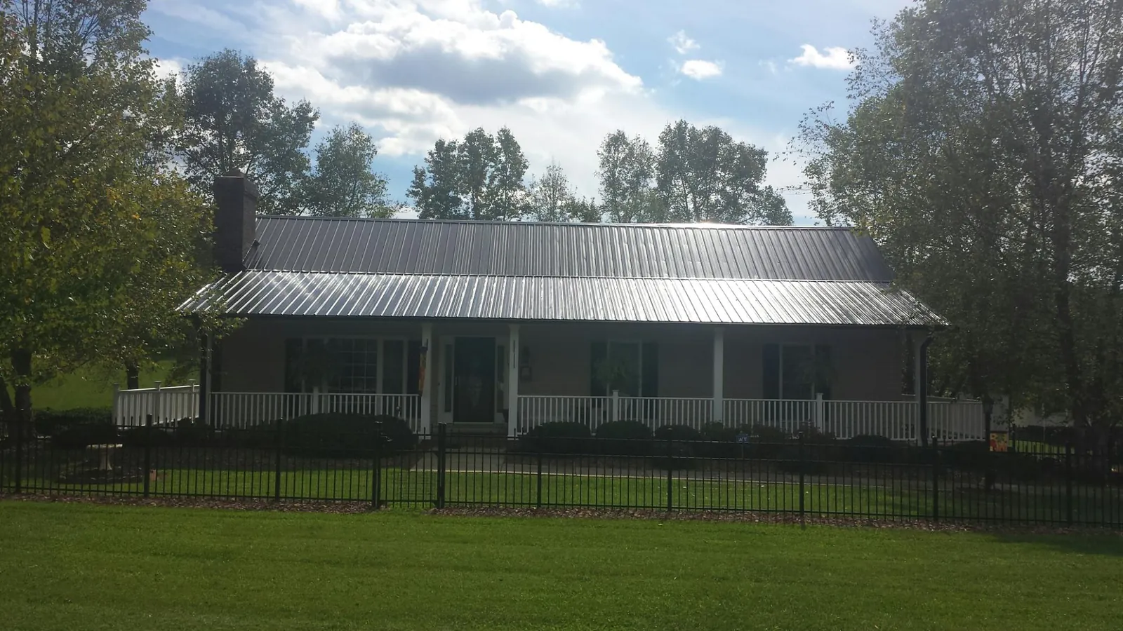 Gray metal roof on a brick ranch with a full width front porch — Gutter Guard Installation work by our crew in Beale Afb