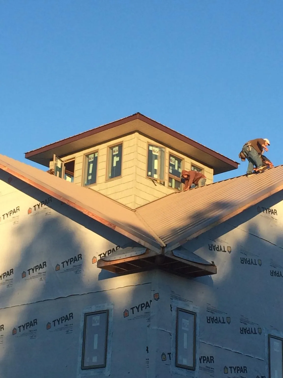 Roofers working around a rooftop cupola on a new metal roof at sunset — Roof Waterproofing in Beale Afb by Roofing Brothers